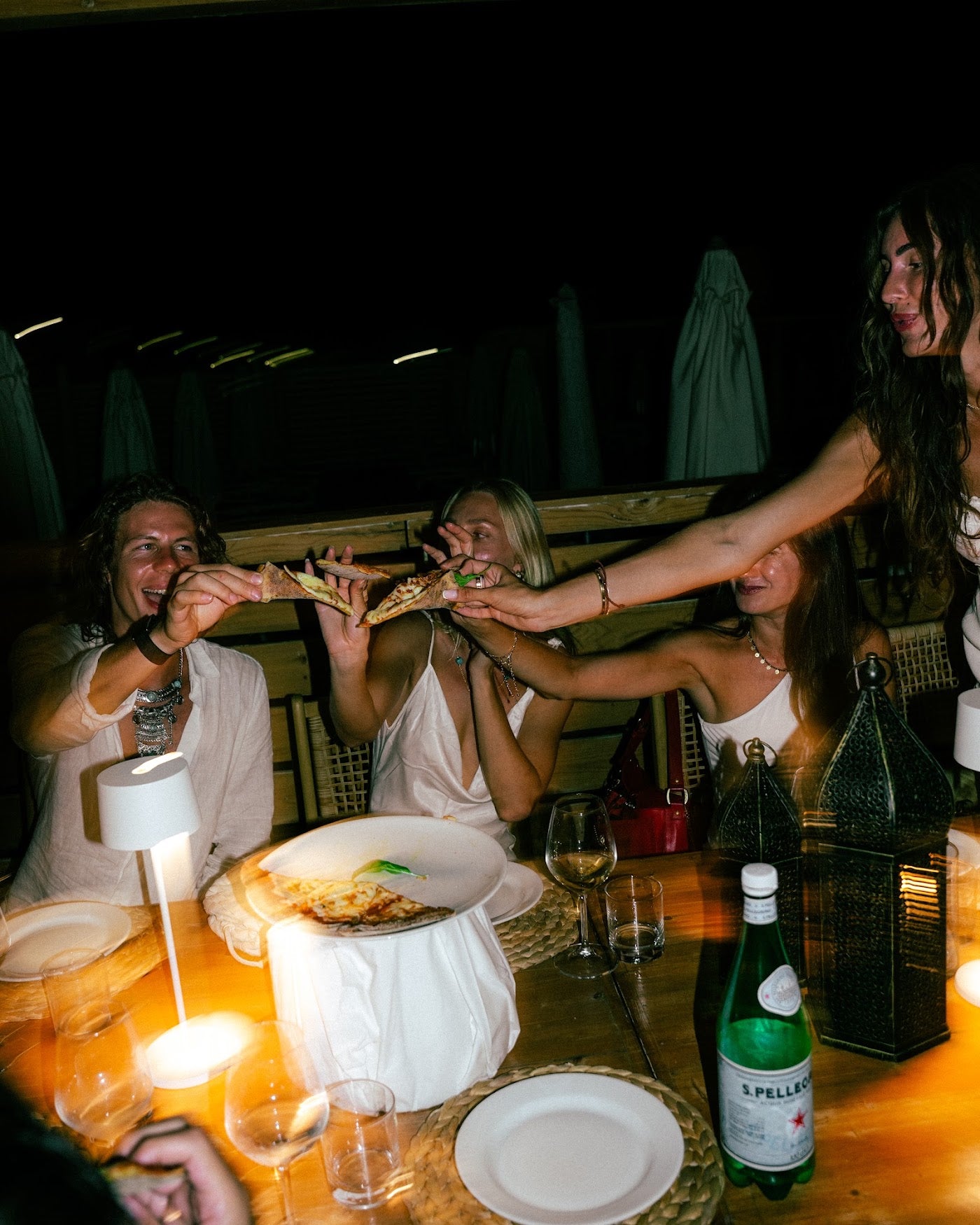 Friends passing slices across the dinner table